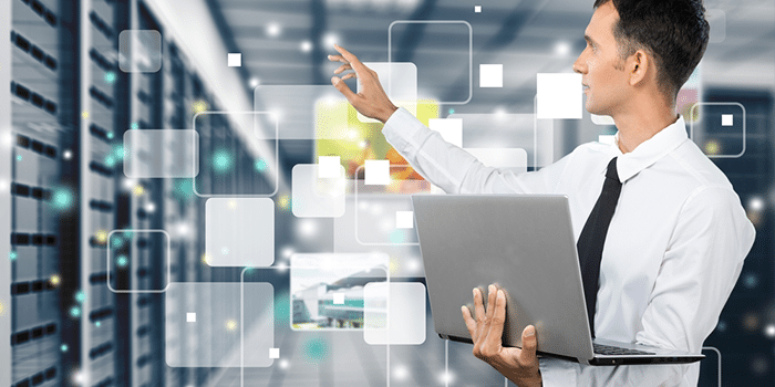 Businessman in a suit holding a laptop while interacting with digital elements in a data center environment.