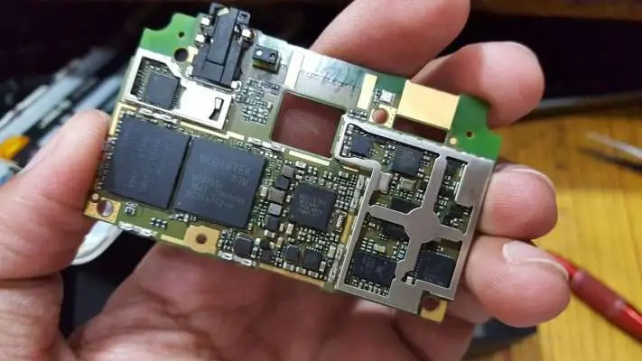 Hand holding a circuit board featuring MediaTek components and various electronic elements.