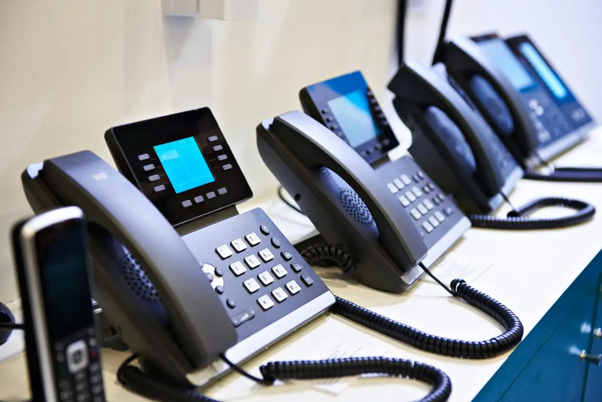 A row of office telephones featuring digital displays and keypads on a countertop.